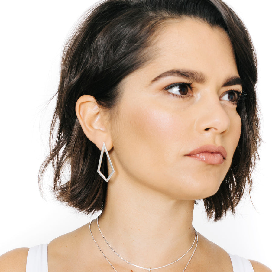 Woman wearing minimalist kite shaped earrings in sterling silver