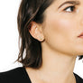Woman wearing minimalist crescent moon earrings in bronze