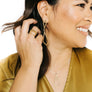 Woman wearing minimalist kite shaped earrings in yellow bronze