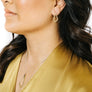 Woman wearing minimalist kite shaped earrings in yellow bronze