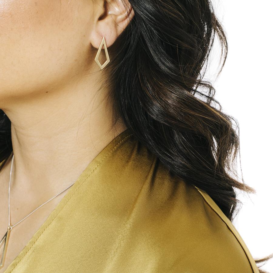 Woman wearing minimalist kite necklace and earrings in yellow bronze