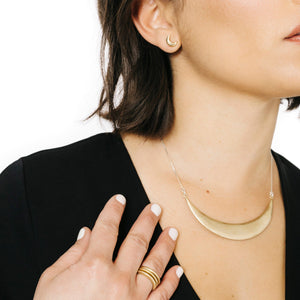 Woman wearing minimalist crescent moon earrings in bronze