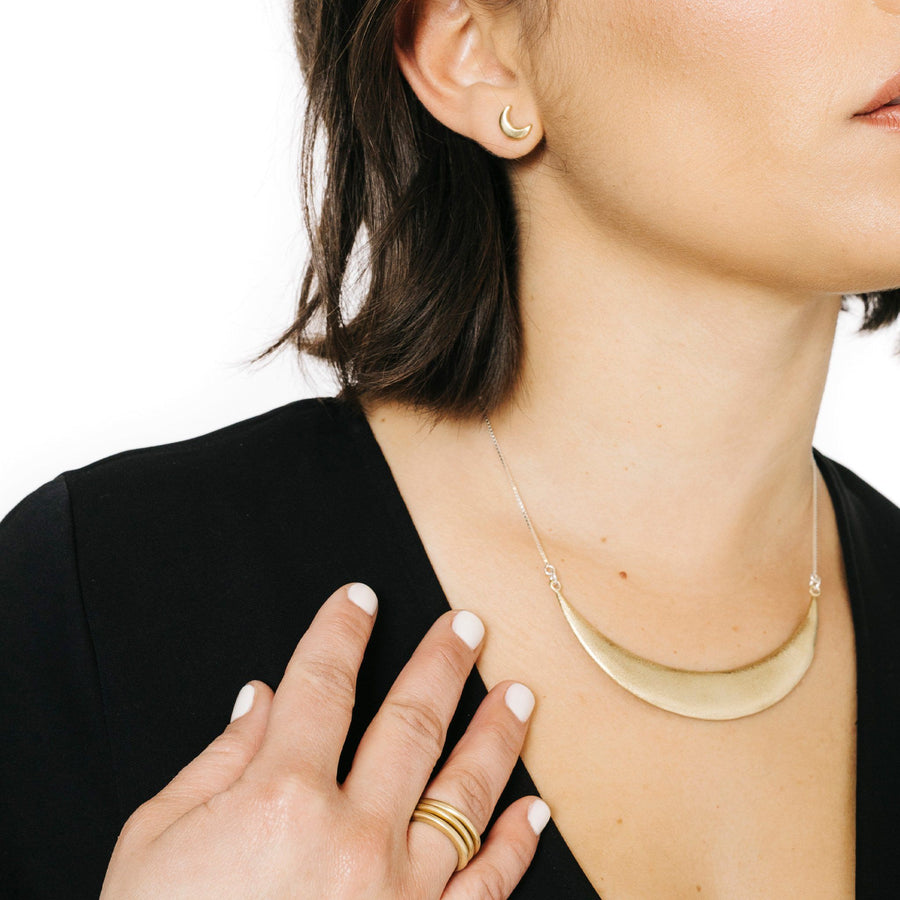 Woman wearing minimalist statement necklace in gold
