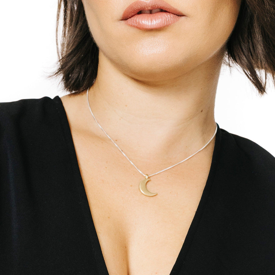Woman wearing minimalist crescent moon necklace in gold