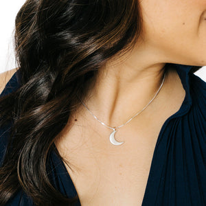 Woman wearing minimalist crescent moon necklace in silver