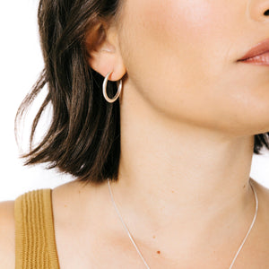 Woman wearing minimalist crescent hoop earrings in gold