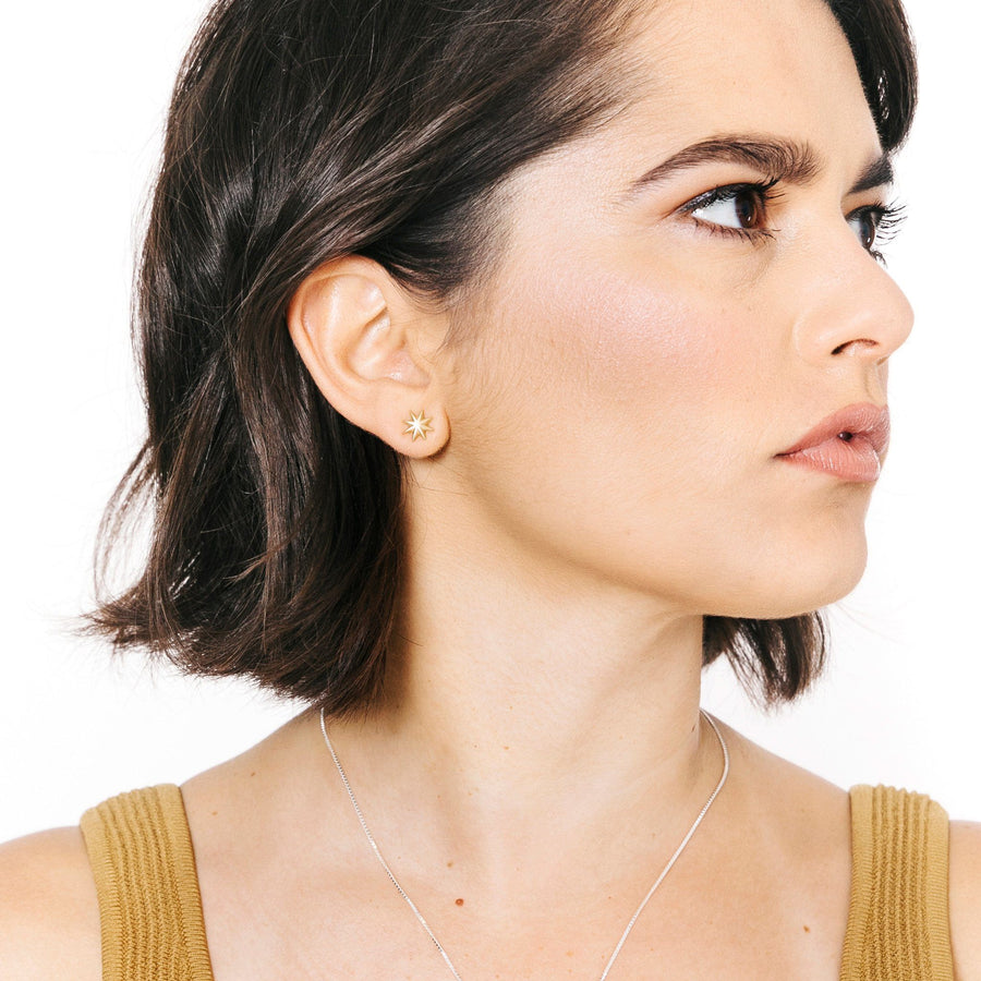Woman wearing minimalist gold star stud earrings